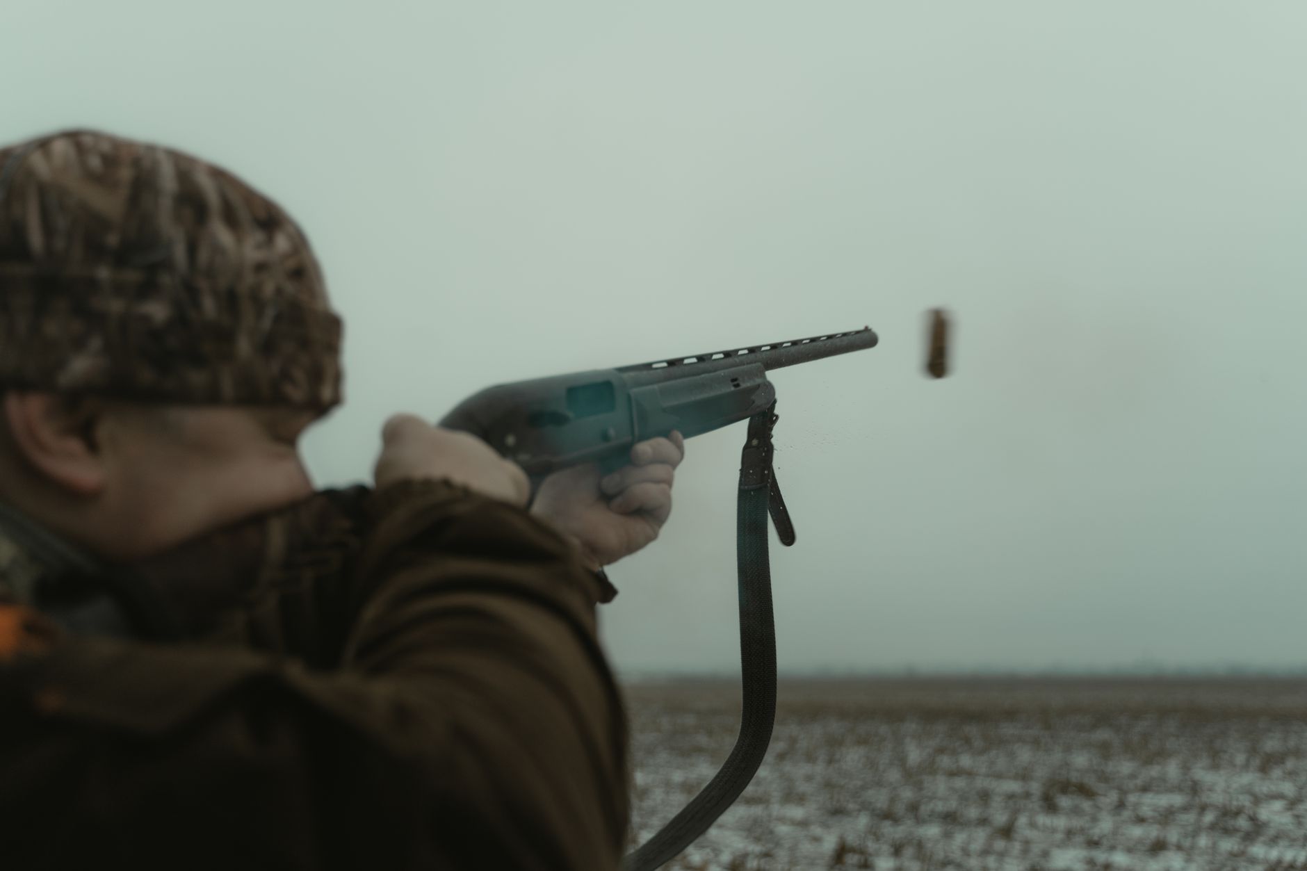 Hunter in camouflage aiming in an open Wyoming field